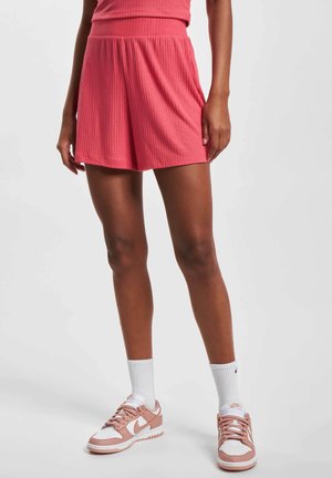 Rosa gerippte Shorts mit einem breiten Bund. Kombiniert mit weißen Socken und rosa Sneakers, die weiße und hellrosa Akzente aufweisen.