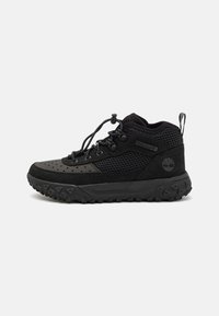 Zapato de senderismo negro con parte superior de malla y ante, suela de goma texturizada y sistema de cordones con ajuste tipo toggle.