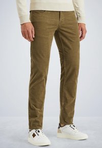 Pantaloni in corduroy marroni con una vestibilità slim, dotati di tasche frontali e una texture morbida, abbinati a sneakers bianche.