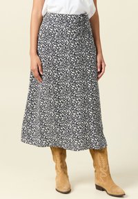 Navy blue maxi-hame, jossa on kukkakuosi ja hulmuava siluetti. Ominaisuuksiin kuuluu korkea vyötärö ja taskut, ja se on viimeistelty vaaleanruskeilla cowboy-kengillä.