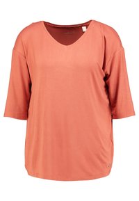 Top a manica corta con scollo a V in corallo, realizzato in tessuto morbido con vestibilità rilassata e spacchi laterali. Include un piccolo dettaglio del logo metallico all'orlo.