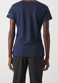 Camiseta de manga corta azul marino con cuello redondo, fabricada en tejido suave, que presenta un logo en la manga y un diseño de corte holgado.
