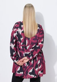 Blusa ampia in un audace motivo astratto rosa, nero e crema. Presenta maniche lunghe e un design a strati sul retro.