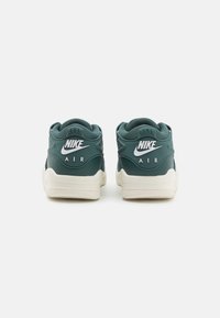 Baskets Nike avec une tige synthétique vert foncé, logo blanc, col rembourré et semelle extérieure en caoutchouc beige. Amorti Air distinctif.