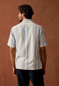 Kurzarmhemd in Weiß mit blauen und rosa vertikalen Streifen; strukturiertes Gewebe mit Button-Down-Kragen und geradem Saum.