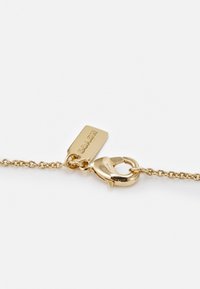 Guldtonet metalarmbånd med kædedesign og en lobsterlukning. Har et lille rektangulært mærke præget med "Coach."