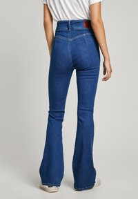Höga vida jeans i mörk denim. Har en läderlapp bak, intrikata sömmar och en figursydd siluett.