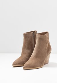 Ruske jestuce ankle boots dengan ujung yang runcing dan tumit koral. Dilengkapi dengan ritsleting samping dan tekstur yang halus.