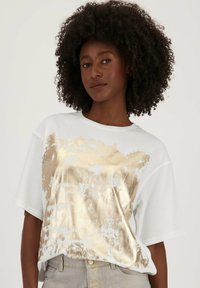 Witte T-shirt met korte mouwen featuring een grote gouden metallic grafiek. Ontspannen pasvorm met een ronde halslijn en een zachte stofstructuur.