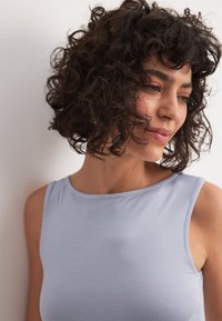 Svetlo modra, brezrokavna majica iz mehke tkanine. Ima okroglo izrez in gladko teksturo, z vidnim šivom ob robovih.