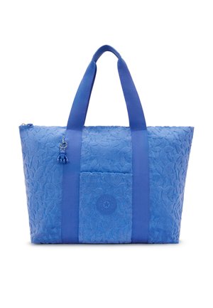 Borsa a mano blu con texture, dotata di due ampie maniglie, tasca frontale con logo circolare e piccolo ciondolo appendente vicino alla maniglia.
