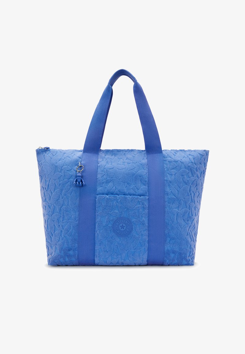 Borsa a mano blu con texture, dotata di due ampie maniglie, tasca frontale con logo circolare e piccolo ciondolo appendente vicino alla maniglia.