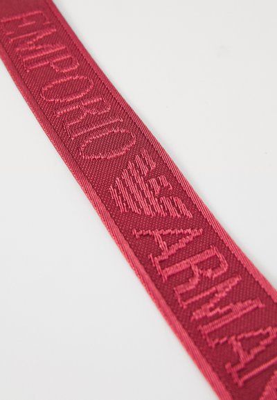 Red woven fabric strap with raised, textured letters spelling "MARMOT AERO" diagonally on a white background.
