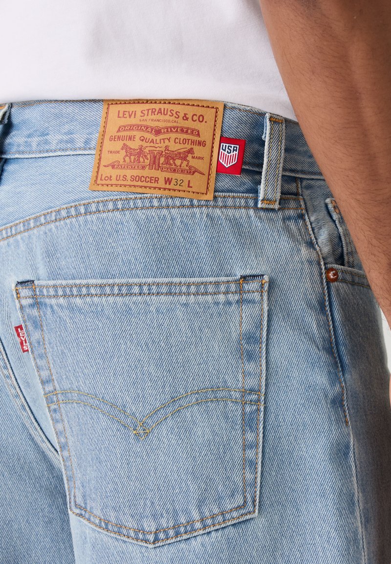Hellblaue Levi's Jeans mit Lederetikett mit dem Schriftzug "Lot U.S. SOCCER W32 L" und einem kleinen roten USA-Tag nahe dem Bund.