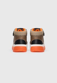 Adidași înalți cu un upper din piele sintetică texturată de culoare maro, accente negre și un interior portocaliu, având o talpă din cauciuc alb și portocalie.