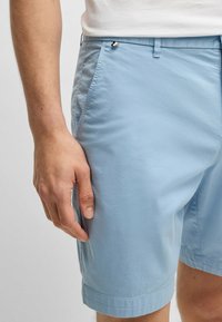 Ljusblå shorts i mjukt material, med sidofickor, en midja med knapp och en rak fåll med subtila broderidetaljer.
