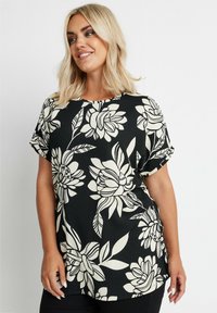 Top corto a maniche corte nero con motivo floreale bianco, scollatura rotonda, vestibilità rilassata, tessuto leggero e testurizzato, completato da maniche arrotolate.