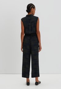 Sleeveless jumpsuit in dark navy with vertical green stripes, featuring a collared neckline, elastic waistband, and wide-leg pants.