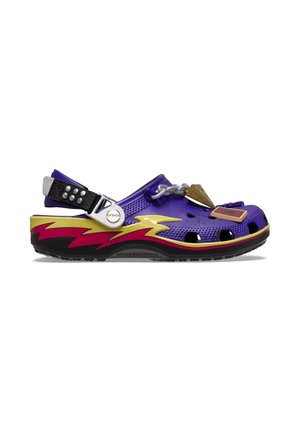 Purple Crocs clog with adjustable black strap, yellow and red lightning design on sole, and attached decorative charms on top.