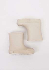 Bottes en caoutchouc beige à chevilles avec un haut arrondi, une semelle texturée et une surface lisse ; logo sur le côté.