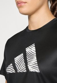 Black athletic t-shirt with a rounded neckline featuring a large white zebra-striped logo. Smooth texture, short sleeves.