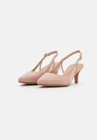 Chaussures slingback en suede rose avec un bout pointu, un petit talon, et une sangle réglable avec un détail de boucle en or. Doublure intérieure lisse.