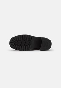 Semelle de chaussure en caoutchouc noir avec des motifs de semelle profonds, présentant des designs angulaires et arrondis pour l'adhérence. Texture lisse et construction robuste.