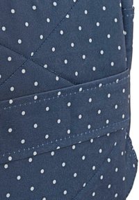 Tela azul con lunares blancos, diseño acolchado, que presenta bandas de costura horizontales y un bolsillo lateral.