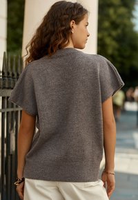 Gray knit short-sleeve top with a ribbed hem and collar. Soft texture, loose fit, and minimal design details. No noticeable patterns or hardware.