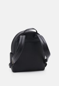 Zaino in pelle nera con forma arrotondata, superficie testurizzata, doppie spalline e una piccola maniglia superiore per il trasporto.