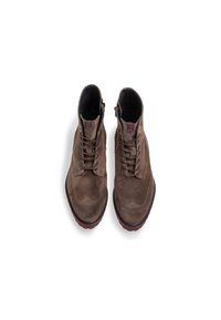 Brown suede ankle boots with a rounded toe, lace-up design, and a small zipper on the side; textured upper and contrasting red sole.