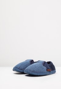 Blauwe stoffen slippers met een textuur bovenkant, elastische randen en een duurzame zool. Bevat een rode logo-accent aan de zijkant.