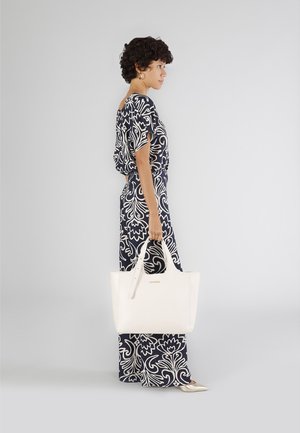 Witte leren tas met stevige handvatten, met een minimalistisch ontwerp en subtiele stikdetails. Achtergrond is lichtgrijs.