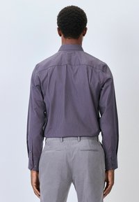 Langärmliges Hemd aus dunkelviolettem Stoff mit einem dezenten geometrischen Muster. Verfügt über einen klassischen Kragen und Knopfmanschetten.