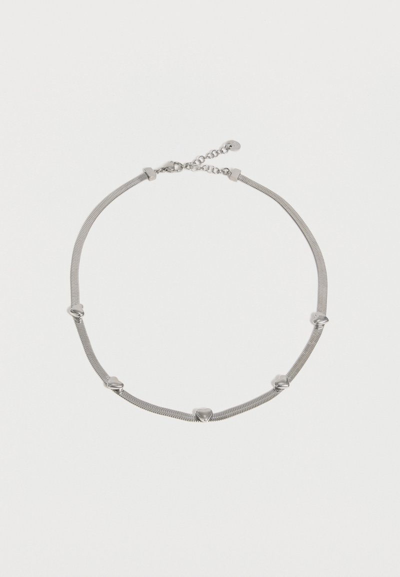 Collier chaîne en argent avec six petits pendentifs en forme de cœur espacés uniformément et un fermoir réglable sur un fond uni.
