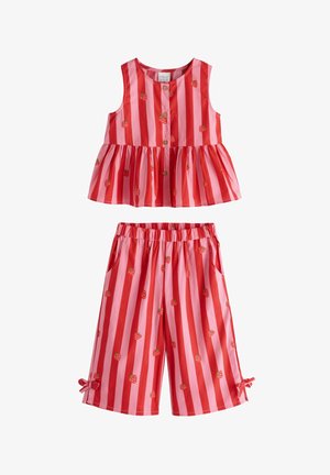 Rød- og pinkstribet peplumtopp med jordbærprints, kombineret med matchende cropped bukser. Fremhævet med sløjfer ved kanten og blomstrede sandaler.