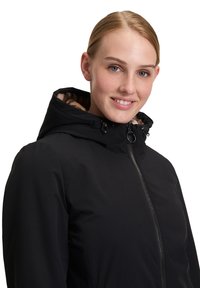 Czarna wodoodporna kurtka z wysokim kołnierzem, zapinana na zamek, z kapturem na sznurku; wyłożona miękkim, wzorzystym wnętrzem dla dodatkowego ciepła.