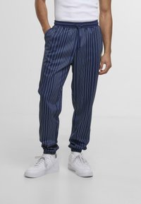Jogging pantaloni a righe navy con vita ed orli elasticizzati, realizzati in tessuto morbido. Presentano tasche laterali e un cordino per la regolazione.