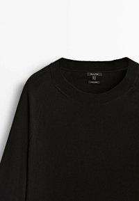 Black pullover sweater with a crew neck, made of soft material, featuring ribbed neck and cuffs, and raglan sleeves.