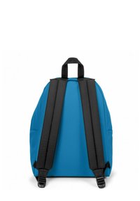 Mochila azul con correas negras, forma redondeada, textura suave y un asa en la parte superior. Cuenta con bolsillos laterales para almacenamiento adicional.