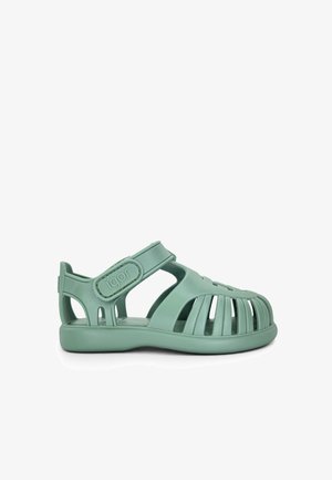 Sandalia infantil de goma verde con diseño troquelado y tira ajustable de velcro con la marca "igor" en el lateral.
