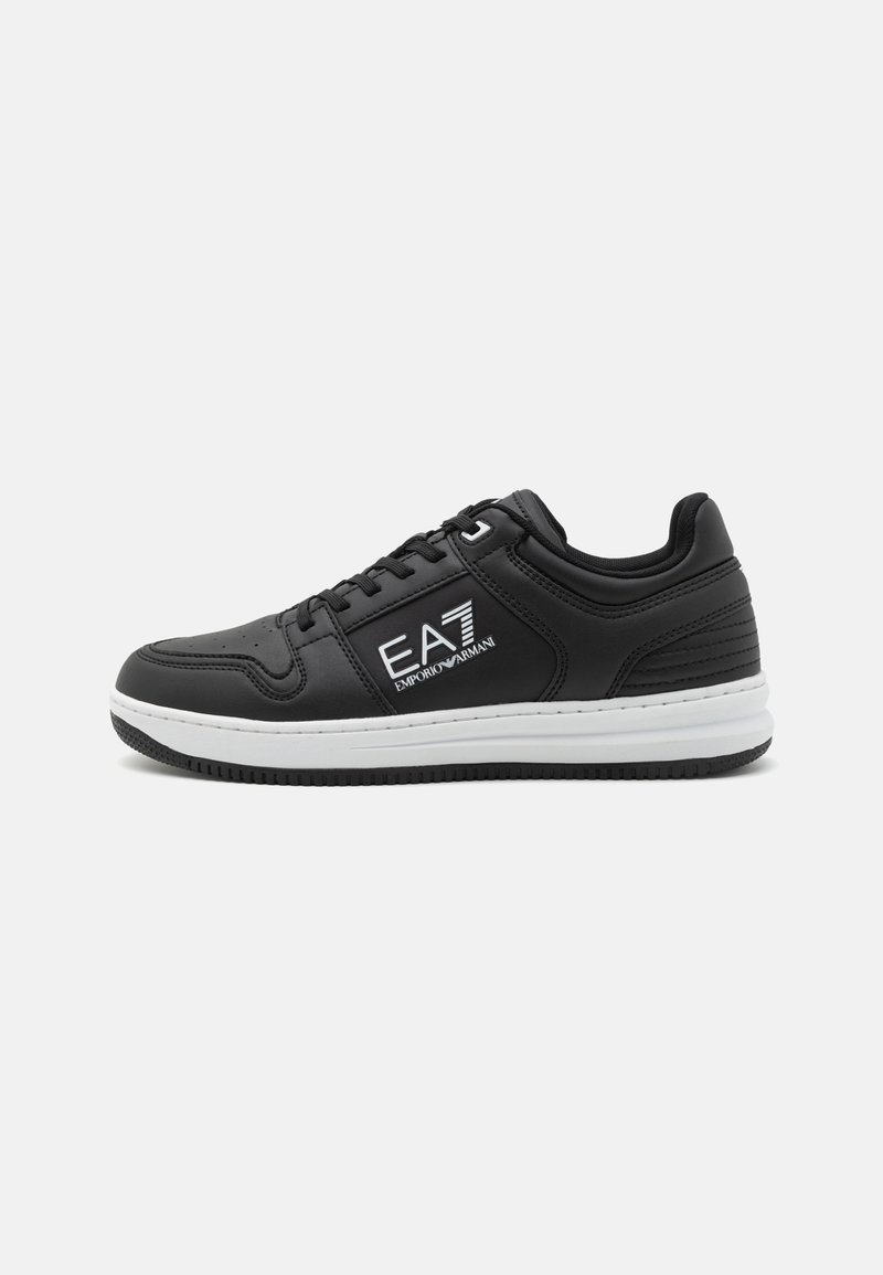 Sneaker in pelle nera con suola bianca, dotato di un logo sul lato, punta arrotondata, perforazioni per la traspirabilità e dettagli testurizzati.