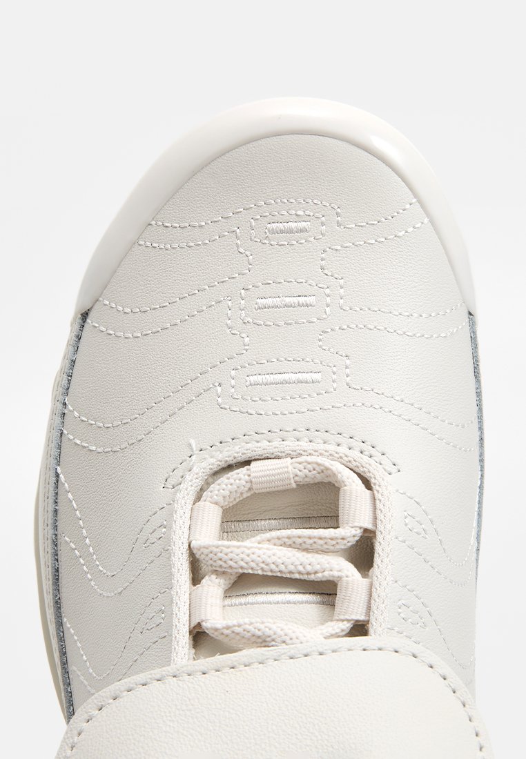 Weiße Leder-Sneaker mit strukturiertem Nähten, einer abgerundeten Zehenpartie und flachen Schnürsenkeln. Die Seitenpartie zeigt metallische Akzente.