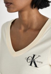 Calvin Klein Jeans MONOLOGO V NECK TEE - Triko s potiskem - vanilla