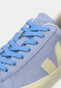 Ανοιχτό μπλε σουέντ αθλητικό παπούτσι με κορδόνια στο ίδιο μπλε χρώμα και εκρού λογότυπο "V" στο πλάι πάνω από εκρού λάστιχο σόλα.