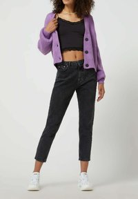 Paarse geribbelde cardigan met zwarte kanten rand, hooggerande zwarte spijkerbroek en witte sneakers. Casual outfit met knoopdetails.
