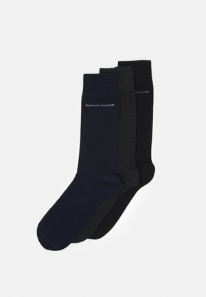 Three pairs of socks in navy blue, dark gray, and black. Each sock features a ribbed cuff and embossed brand logo near the top.