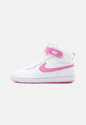 Baskets montantes blanches Nike avec virgule rose, bride à la cheville et accents sur la semelle, sur fond gris clair uni.