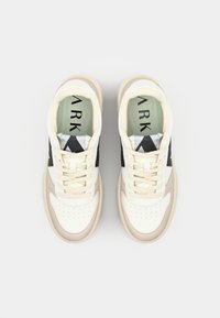 Sneakers w białej i beżowej skórze z czarnymi akcentami, z zaokrąglonym noskiem, sznurowanym przodem, wyściełanym kołnierzem i teksturowaną gumową podeszwą.