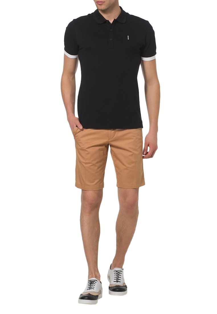 Polo noir avec des accents blancs, shorts beiges et chaussures à lacets noir et blanc. La tenue présente une coupe slim.